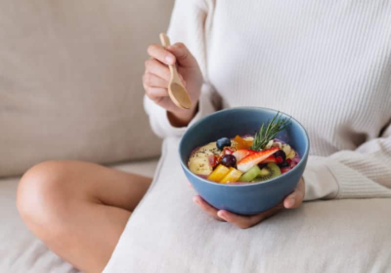 foto de pessoa sentada com tigela de alimentos saudáveis
