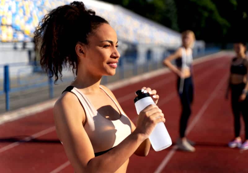 mulher bebendo agua parada na pista de corrida