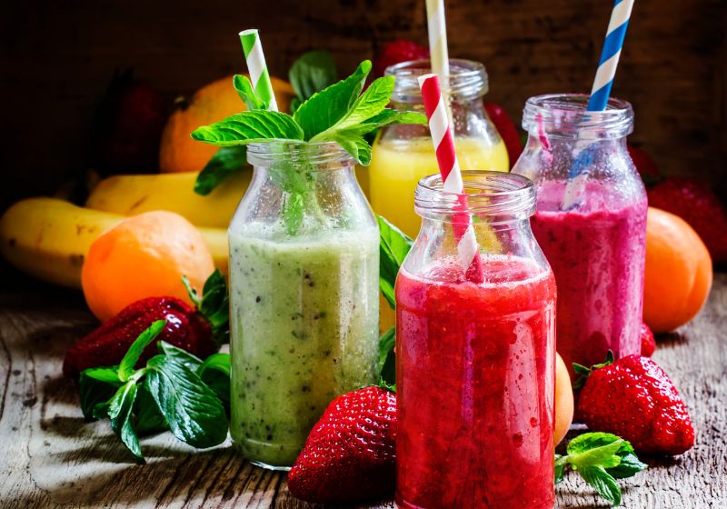 Vitamina de frutas com leite vitaminas de fruta em umas garrafinha de vidro com morango e outras frutas ao lado