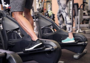 pernas de um homem e de mulher fazendo elítico