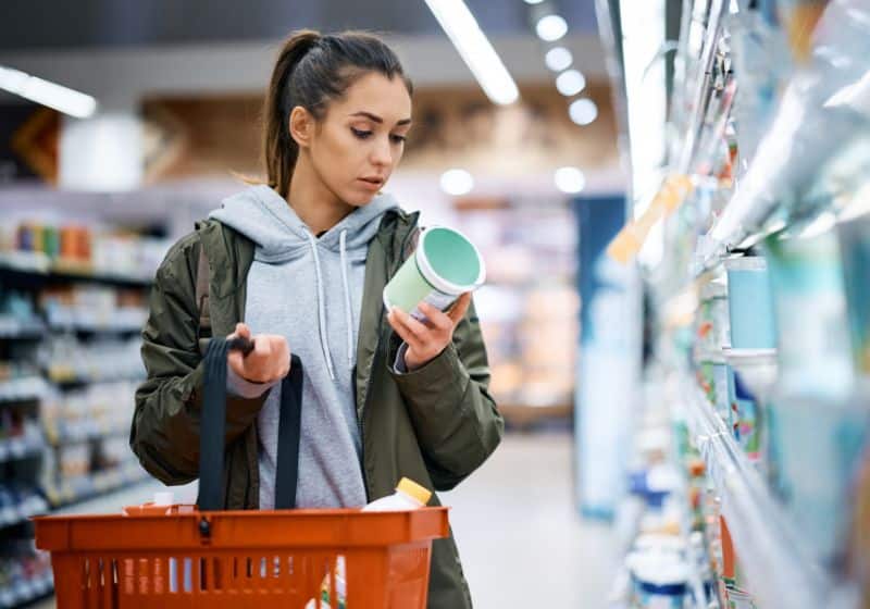 mulher em um mercado fazendo compras e lendo os rótulos dos alimentos 