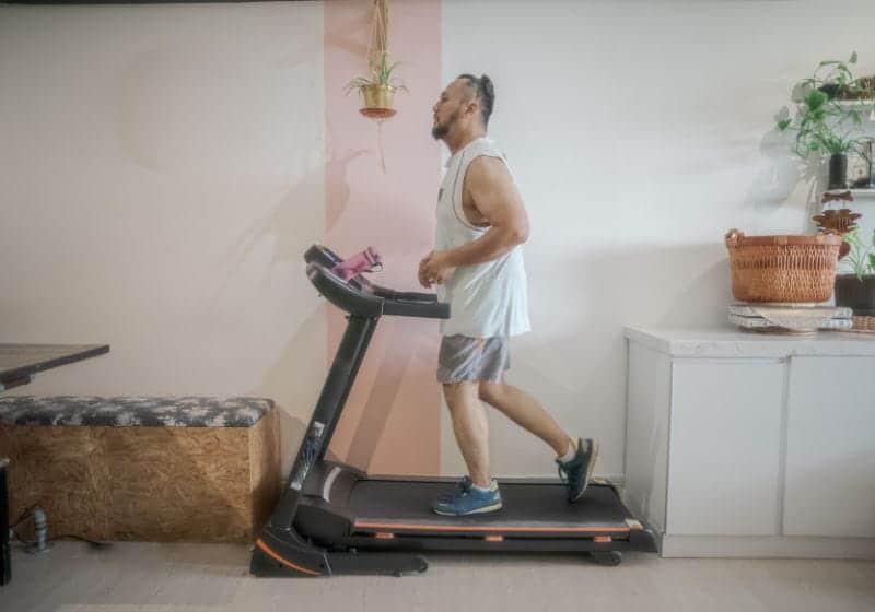 homem em cima de um esteira preta e laranja e um armario do lado