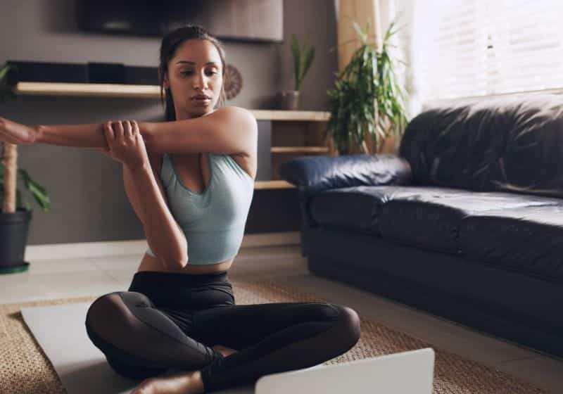 Mulher fazendo alongamento em casa