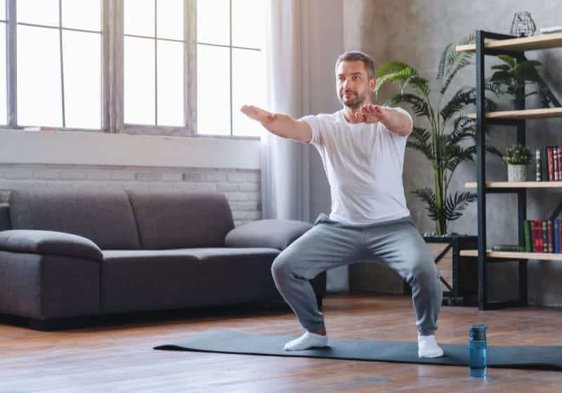Homem fazendo treino agachamento isométrico em casa