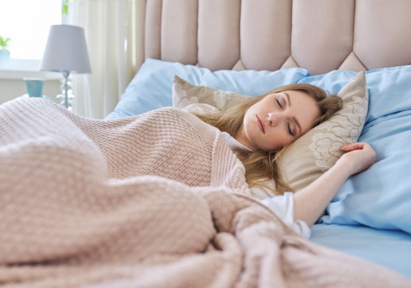 mulher deitada em sua cama com sua coberta rosa, dormindo 