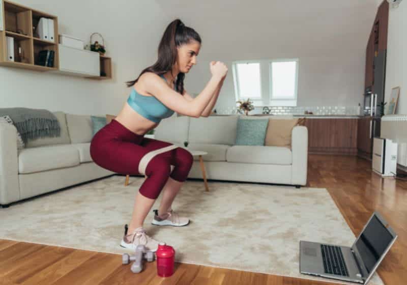 Mulher fazendo treino agachamento em casa