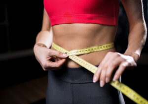 mulher com um fita métrica na barriga vendo se emagreceu