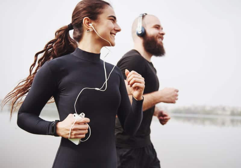 casal correndo ao ar livre exercitando juntos com fone de ouvido 