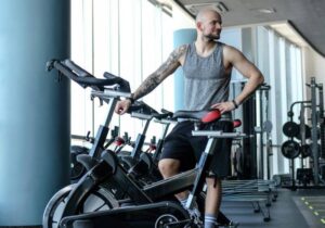 homem na academia apoiado ema bicicleta ergométrica