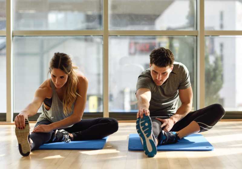 Casal se alongando antes de iniciar as atividades físicas