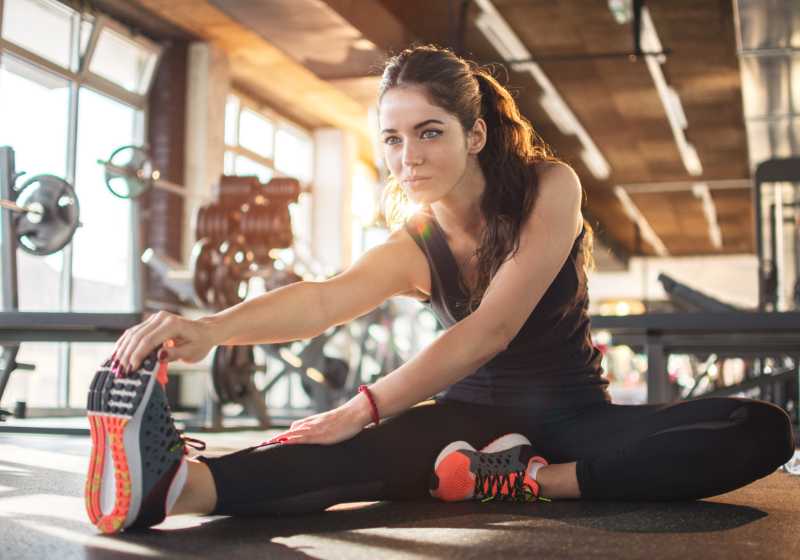 Mulher sentada se alongando após os exercícios físicos