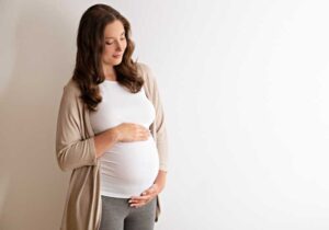 Mulher grávida com as mãos na sua barriga