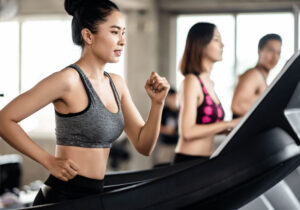 Duas mulheres e um homem praticando atividade física na esteira