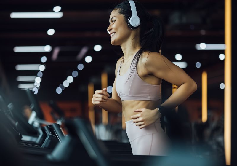 146664eb74768fa8c890d098755557a2_18 Mulher escutando música em seu fone e correndo em uma esteira