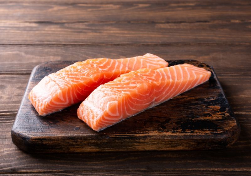 Dois pedaços de salmão em cima de uma tábua de madeira