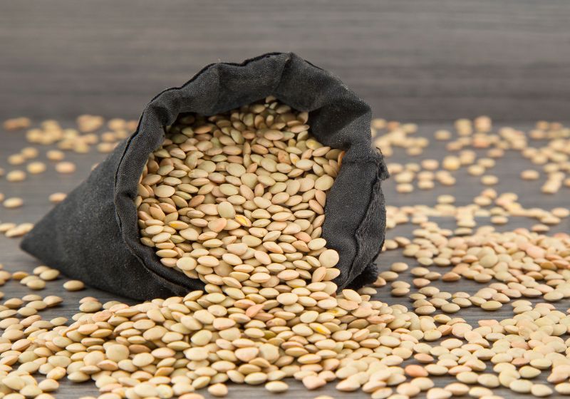 Um saco preto em cima de uma mesa com várias lentilhas