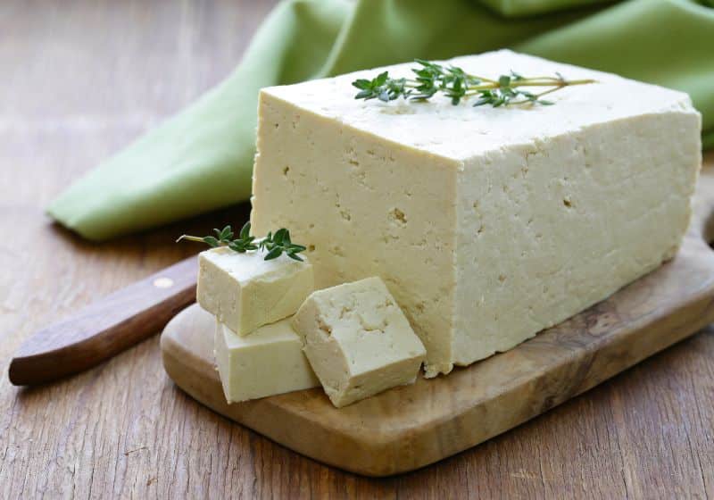 Uma peça de tofu em cima de uma tábua de madeira