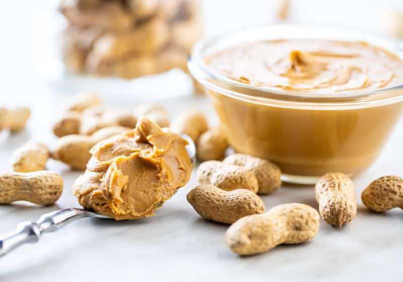 Um pote e uma colher com pasta de amendoim