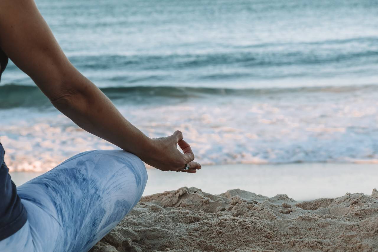 Mulher praticando yoga na praia