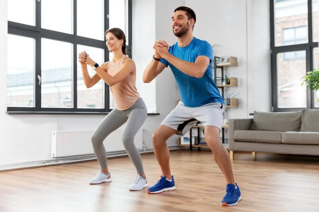 Couple practicing free squat exercise in indoor environment