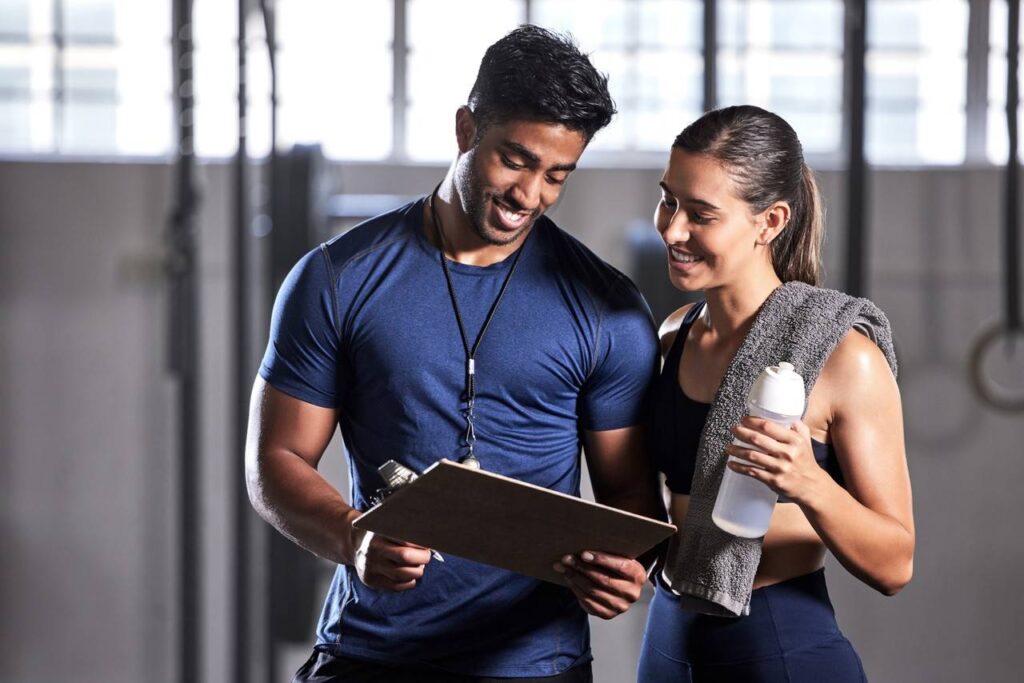 Personal trainer orientando aluna com indicações em prancheta