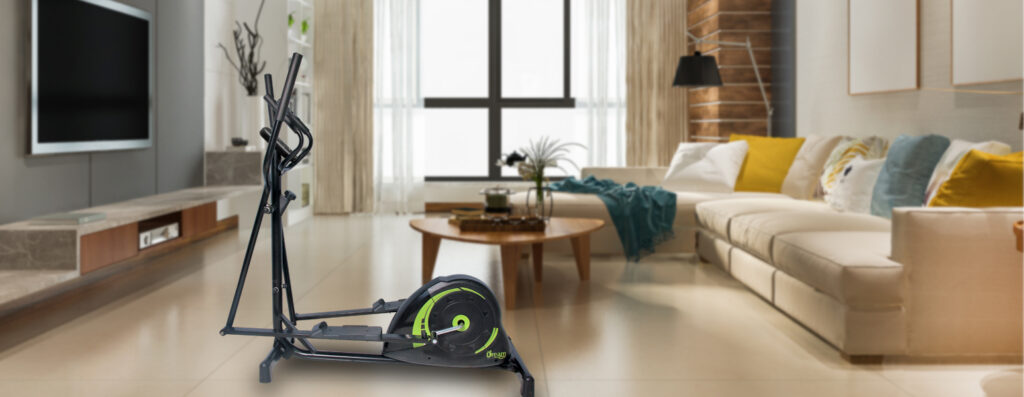 Elíptico Dream CONCEPT E posicionado em uma sala de estar moderna com piso de madeira, tapete geométrico em tons de verde e azul, e móveis elegantes ao fundo, incluindo poltrona verde, sofá claro com almofadas coloridas e mesa de centro decorada.