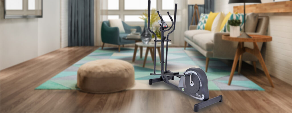 Elíptico Dream MAG 5000E com detalhes verdes em destaque no centro de uma sala de estar sofisticada, com sofá claro em 'L', mesa de centro de madeira, decoração aconchegante com almofadas coloridas e ampla janela ao fundo iluminando o ambiente.